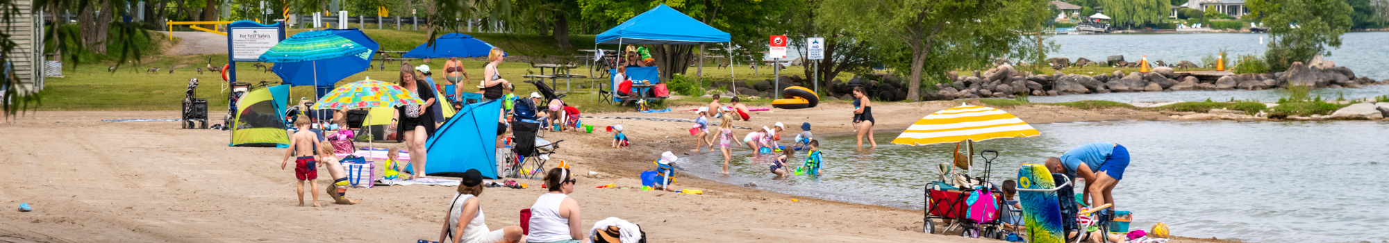 crowded beach with lots of families playin in sand and swimming